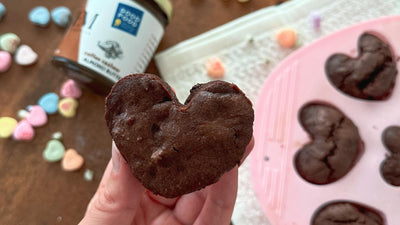 Brownies shaped like hearts with heart shaped candies scattered on the table