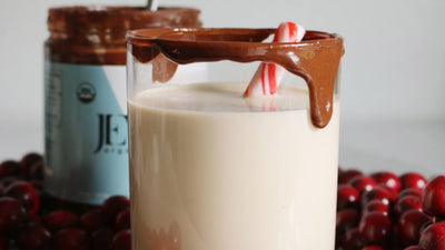 White russian drink with a peppermint stick in the glass and a jar of JEM Organics Nut Butter