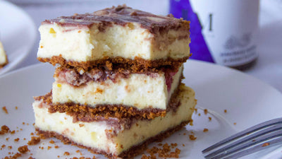elderberry nut butter topped cheesecake bars stacked on a white plate
