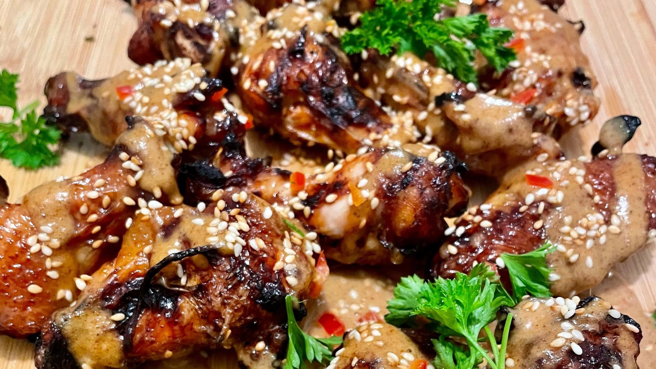 thai chicken wings with a nut butter sauce on a wood cutting board