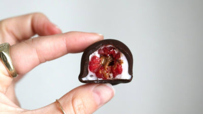 Frozen raspberry filled with nut butter covered in yogert and then covered in chocolate