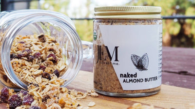 mason jar laying down and spilling granola next to a jar of almond butter