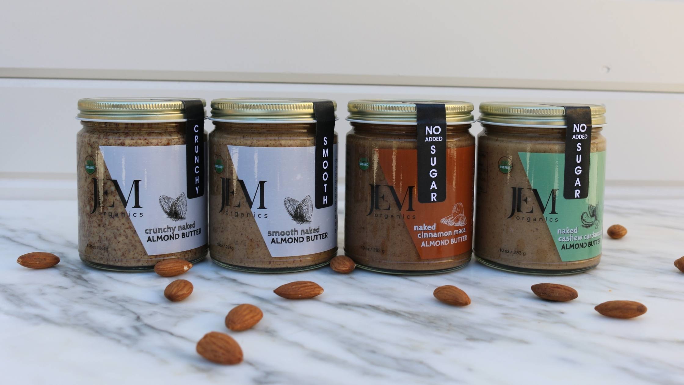 JEM Organics four No Sugar Added nut butters lined up on a marble table