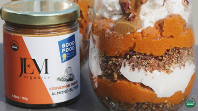 glass jars filled with pumpkin puree, curst and whipped cream next to a nut butter jar